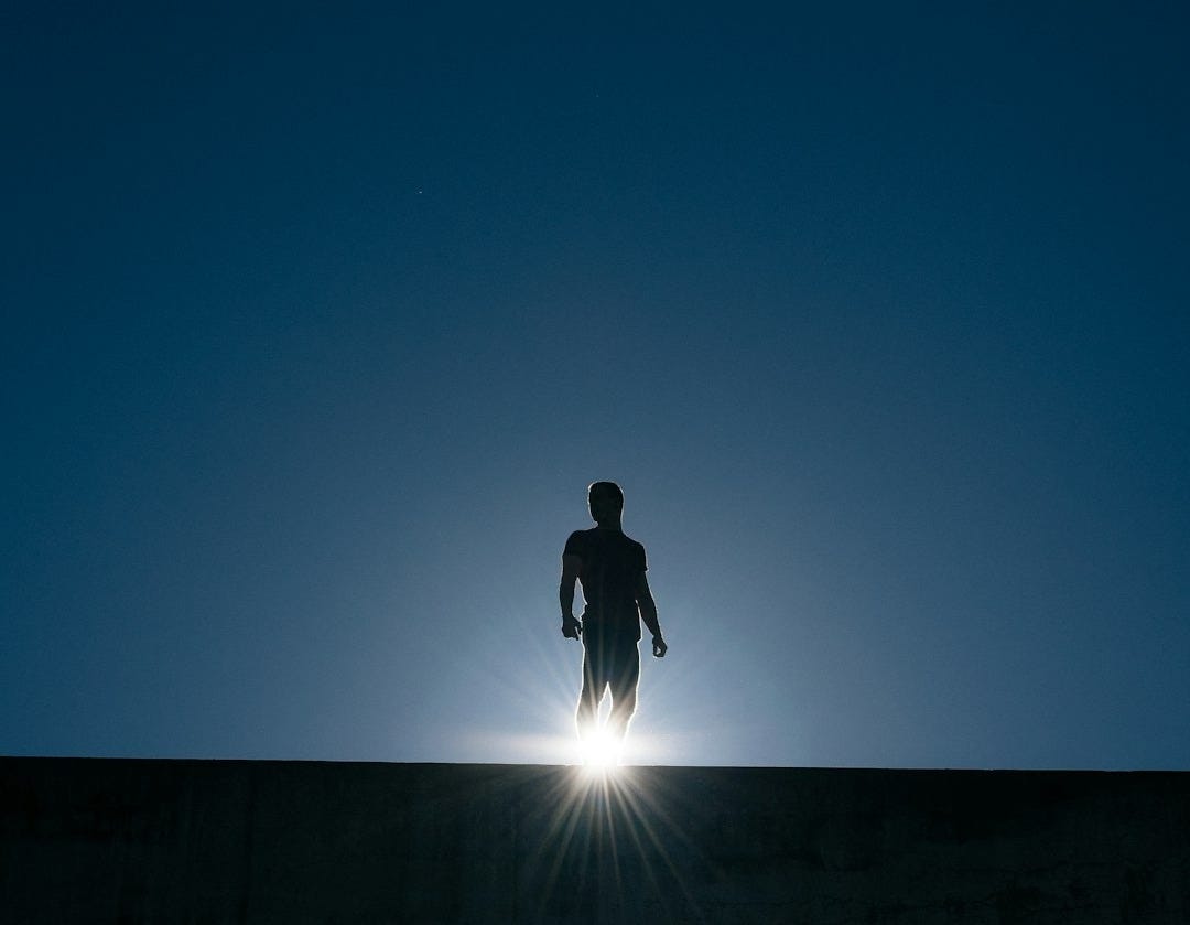 silhouette of man standing on bridge