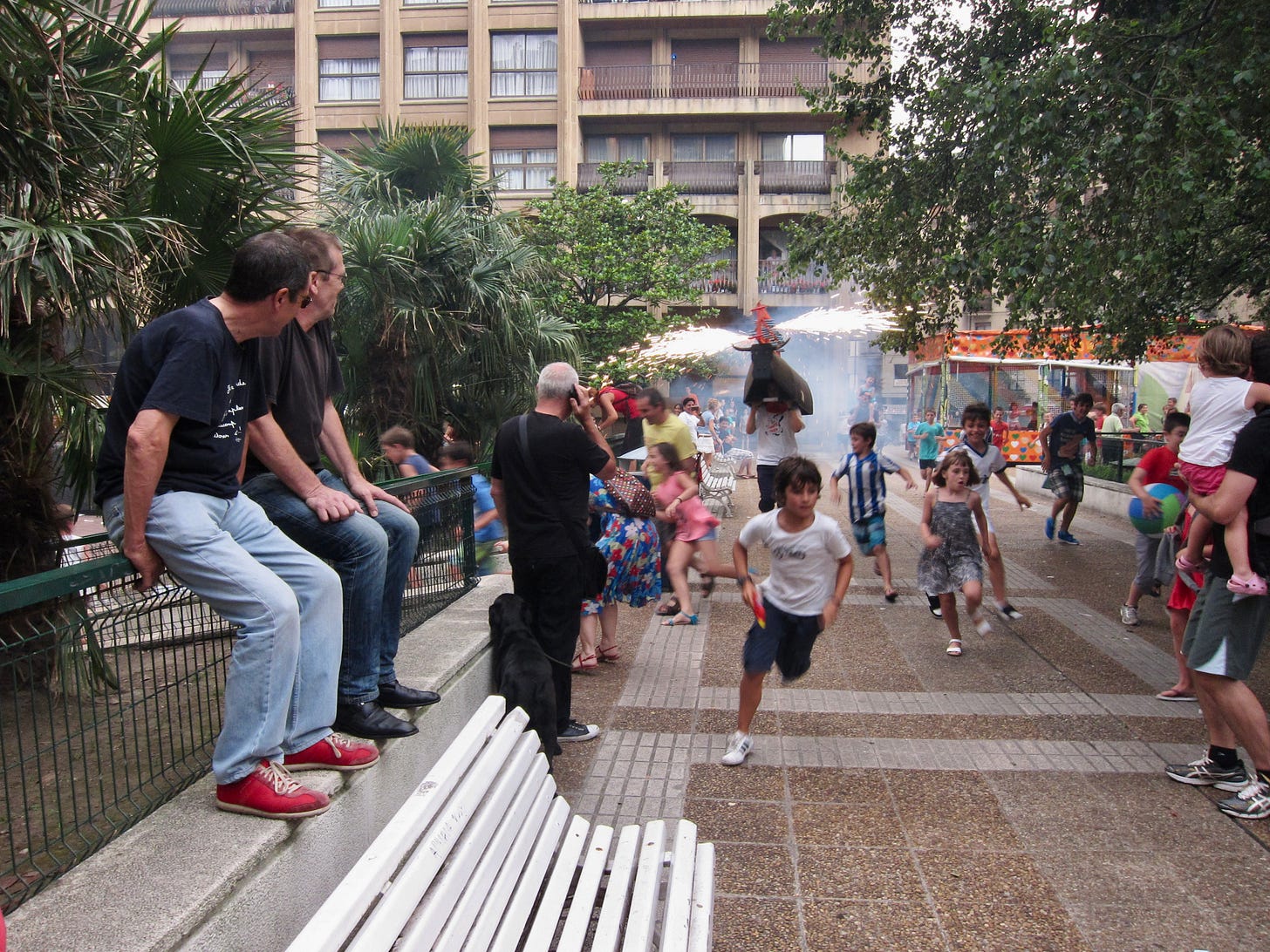 Children running and a pretend bull with fireowrks in the background