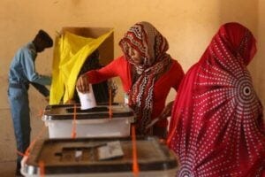 A Sudanese police officer stands at a polling booth as an electoral officer (C) helps a woman cast her vote in the country's elections at a polling station in a classroom in Khartoum's southern suburb of Mayo on April 14, 2015. Mayo is mainly populated with displaced people from Darfur and Kordofan where fighting between rebels and President Omar Al-Bashir troops has forced people from their homes. AFP PHOTO / PATRICK BAZ (Photo credit should read PATRICK BAZ/AFP/Getty Images)