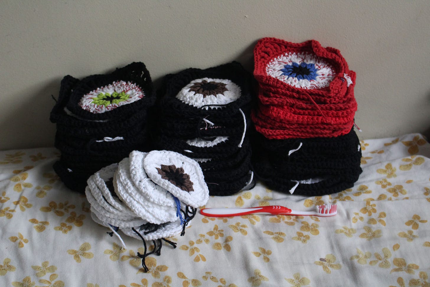 three stacks of crocheted granny squares with a small pile of unfinished squares in front of them