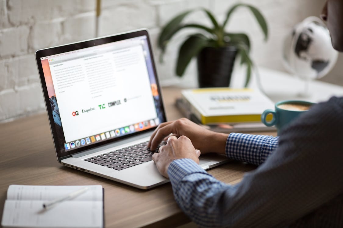 Free A man working on a laptop at a desk with coffee, showcasing remote work in a modern office setting. Stock Photo