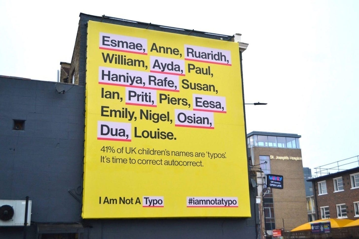 Un cartellone giallo della campagna I Am Not a Typo appeso a una parete cittadina. Il testo dice “Esmae, Anne, Ruaridh, William, Ayda, Paul, Haniya, Rafe, Susan, Ian, Priti, Piers, Eesa, Emiliy, Nigel, Osian, Dua, Louise. Il 41% dei nomi di bambini del Regno Uniti sono considerati errori di battitura.” Esmae, Ruaridh, Ayda, Haniya, Rafe, Priti, Eesa, Osian e Dua sono evidenziati in bianco e sottolineati in rosso come se fossero da correggere. Un cartellone giallo della campagna I Am Not a Typo appeso a una parete cittadina. Il testo dice “Esmae, Anne, Ruaridh, William, Ayda, Paul, Haniya, Rafe, Susan, Ian, Priti, Piers, Eesa, Emiliy, Nigel, Osian, Dua, Louise. Il 41% dei nomi di bambini del Regno Uniti sono considerati errori di battitura.” Esmae, Ruaridh, Ayda, Haniya, Rafe, Priti, Eesa, Osian e Dua sono evidenziati in bianco e sottolineati in rosso come se fossero da correggere.