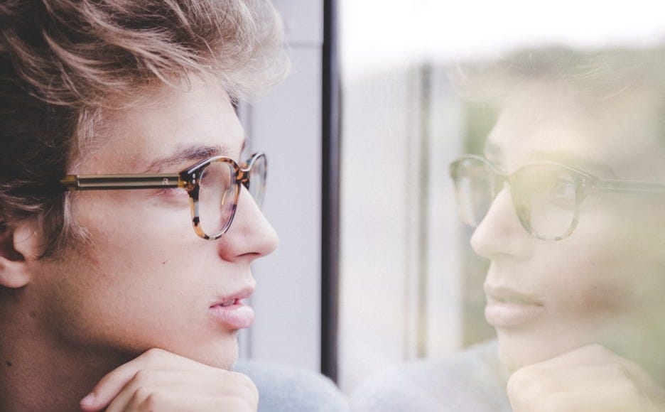 a man wearing glasses looking out a window a man wearing glasses looking out a window