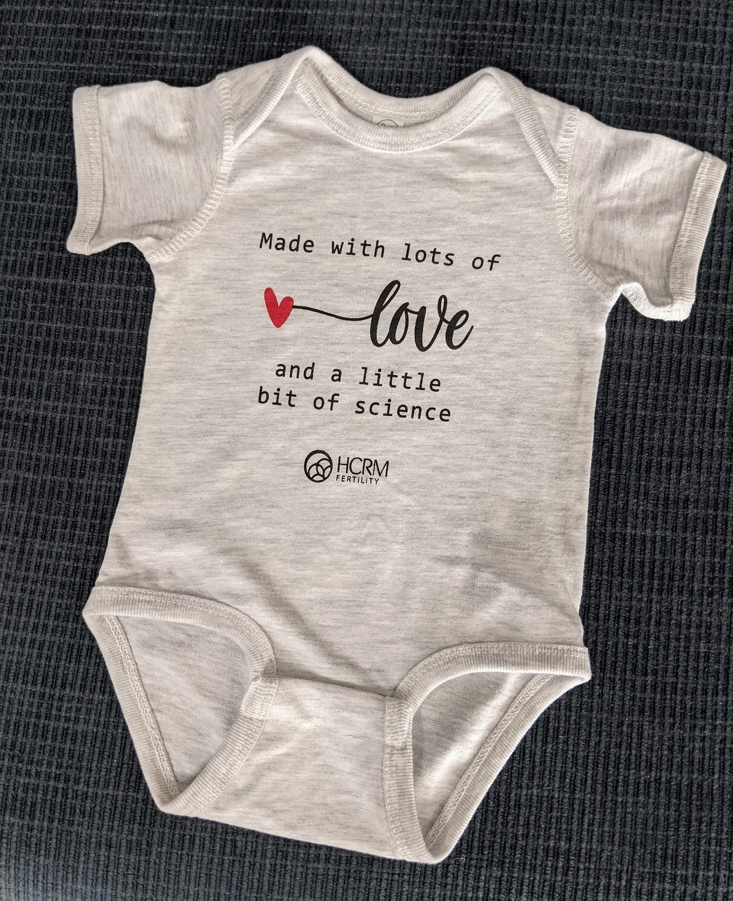 gray baby onesie with text that reads made with lots of love and a little bit of science
