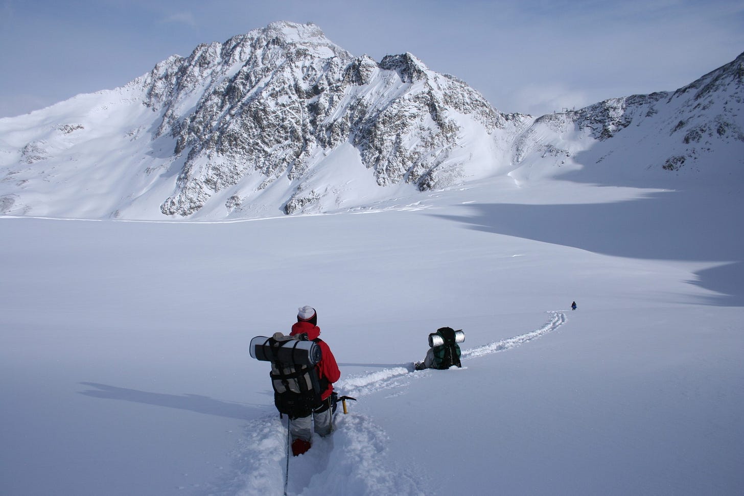 Explorers waist-deep in snow in front of mountains