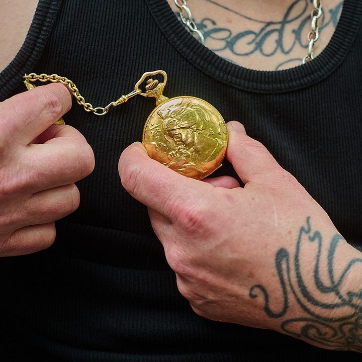 On the left is a close up of Fogel holding the watch in her hands up to her chest so we can see the detail of the woman in gold kissing a dove. On the right is a close up of the other side of the watch on a rusty background. We can see a mother and baby deer.