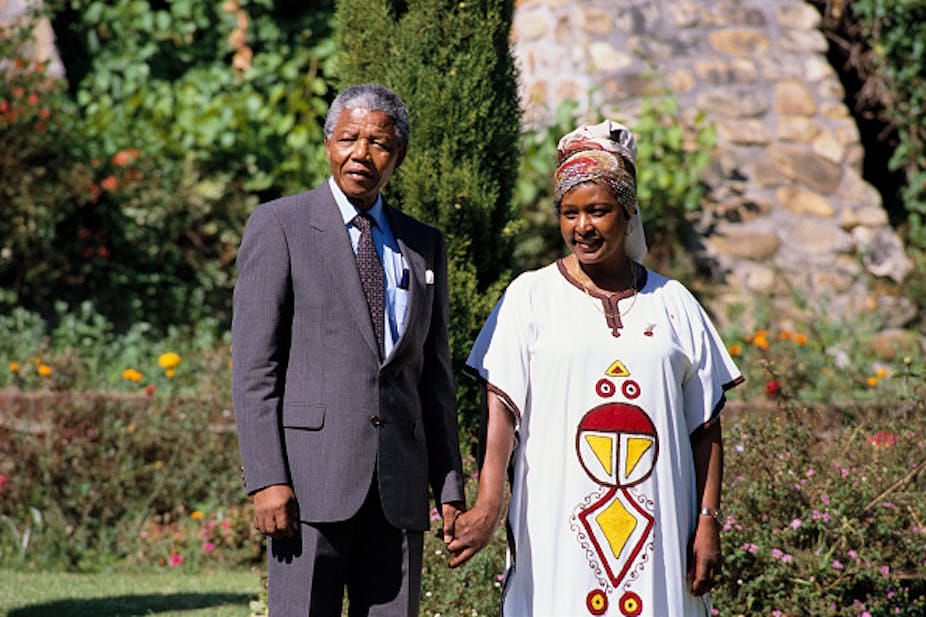 A man wearing a suit holds hands with a woman wearing long African dress and headscarf. A man wearing a suit holds hands with a woman wearing long African dress and headscarf.