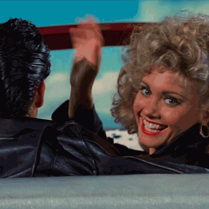 Olivia Newton-John as Sandy waves at the audience over her shoulder as she departs in a flying car with Danny