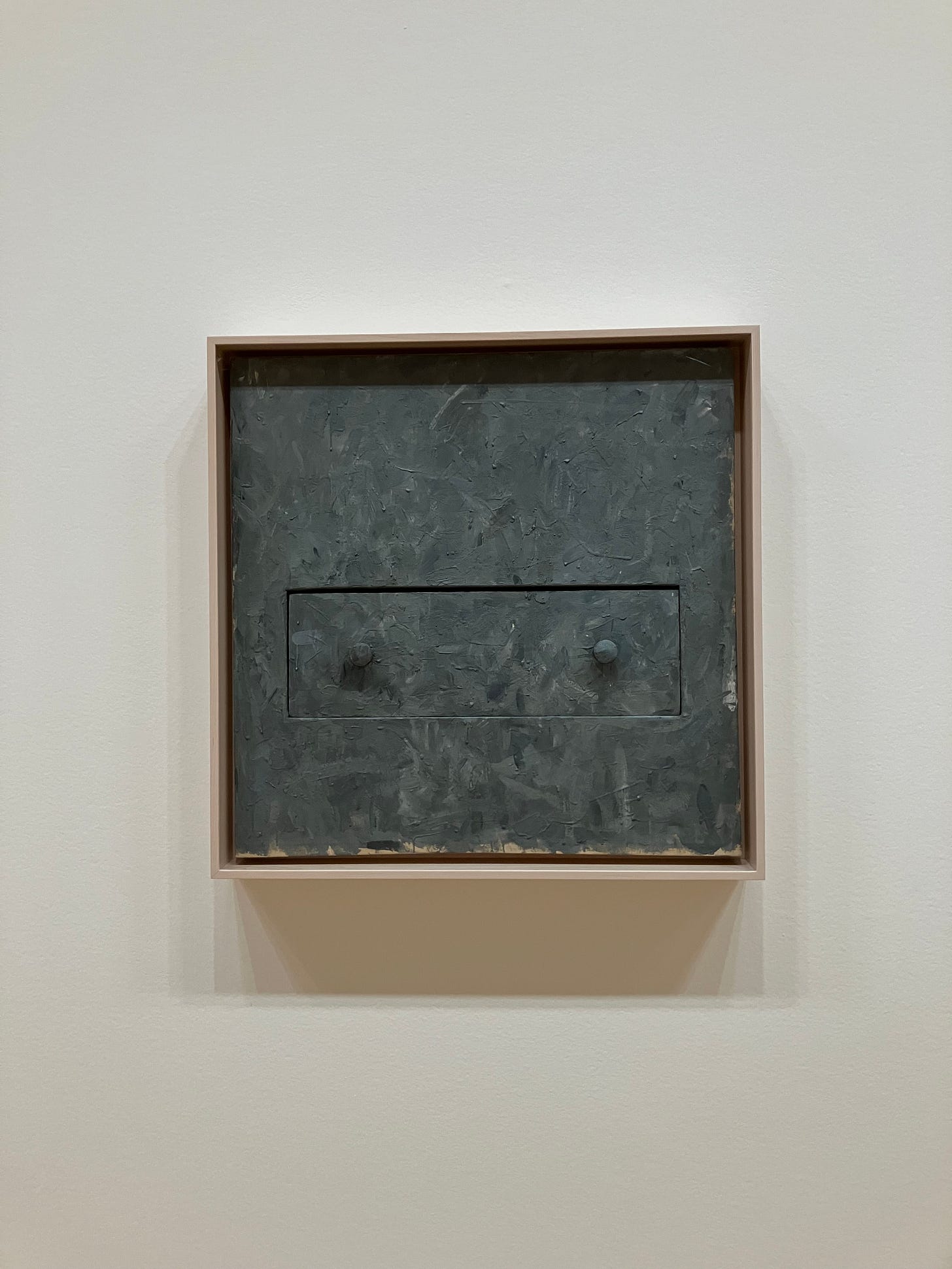 A square gray painting of a drawer in rough brushstrokes with two protruding knobs