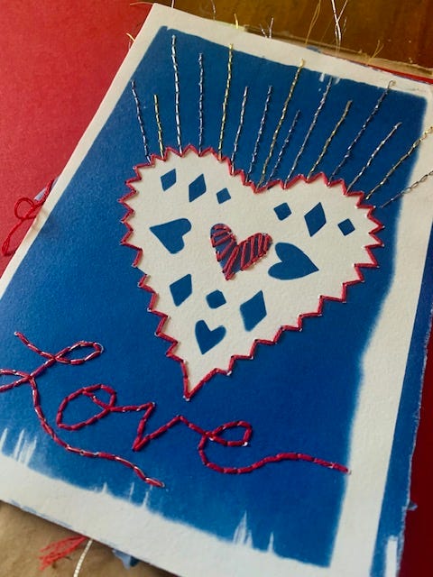 a cyanotype heart with the word LOVE embroidered beneath it