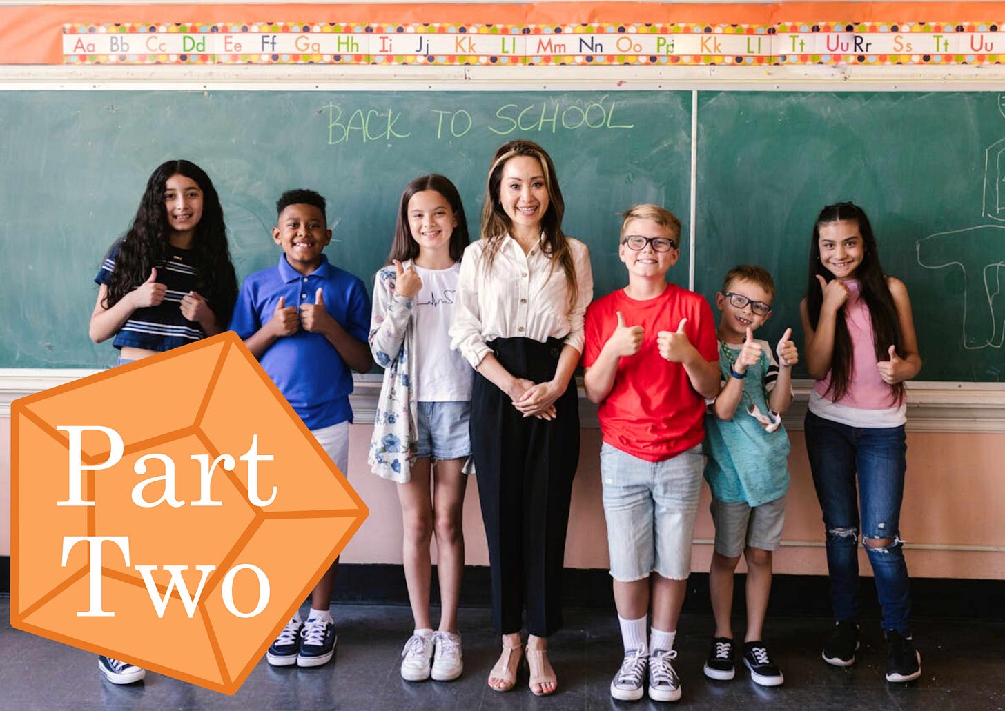 A group of excited kids are standing next to their teacher in front of a blackboard that has “BACK TO SCHOOL” written on it. An orange gem with the words “Part Two” on top of it is placed off to the side of the image.