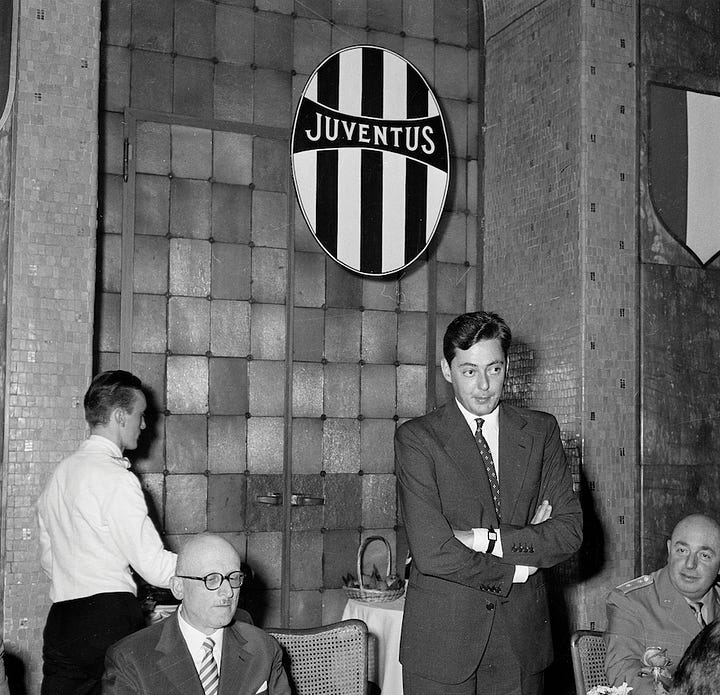 Umberto Agnelli with Juventus officials at a 1950s banquet featuring club crests and commemorative presentations.
