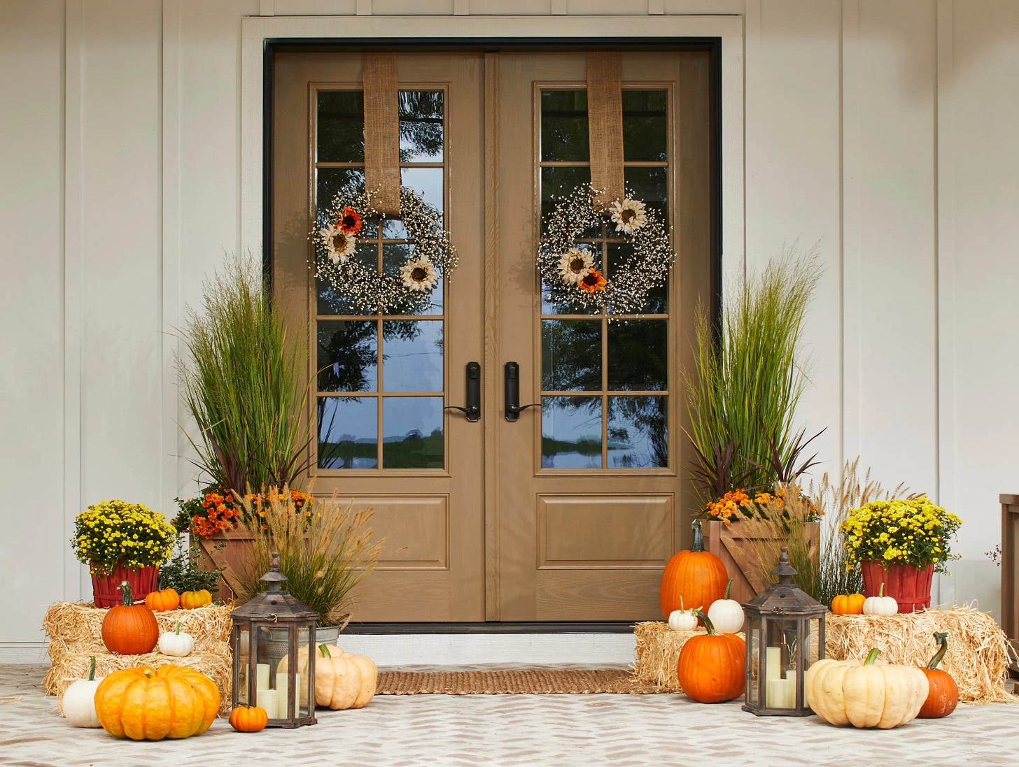 two wood front doors with fall wreaths and pumpkins