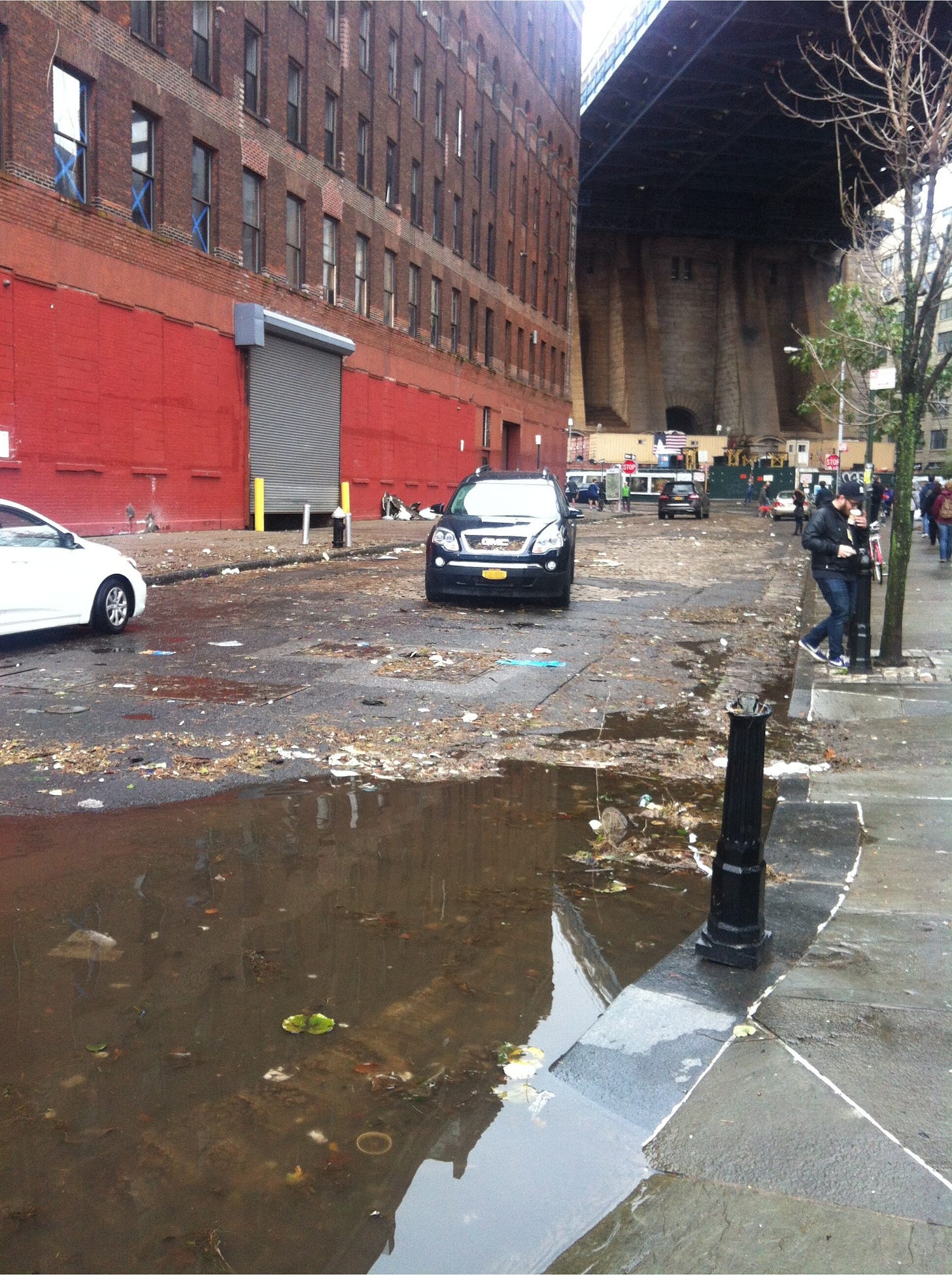 Amber's old GMC Acadia sits in the middle of a partially flooded street. People are walking around and debris covers the ground. Amber's old GMC Acadia sits in the middle of a partially flooded street. People are walking around and debris covers the ground.