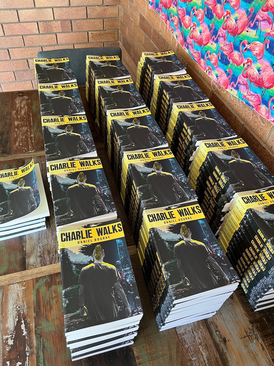 Charlie Walks paperback copies on a table with flamingos in the background