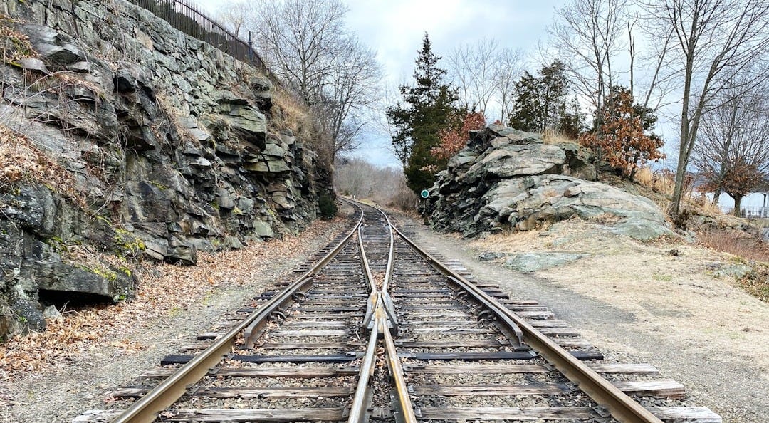 brown metal train rail near rocky mountain during daytime