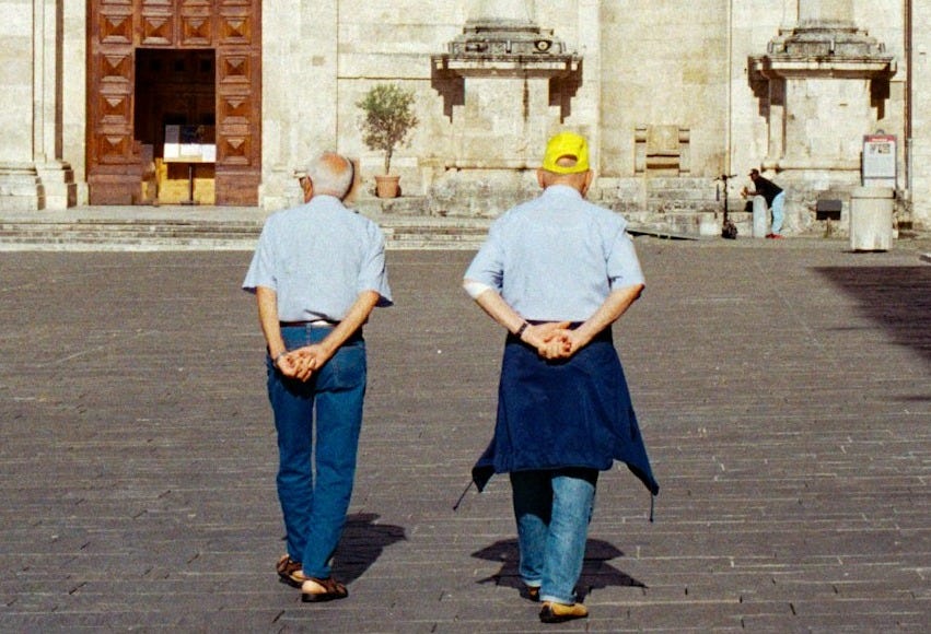 Two people walking towards a large building entrance.