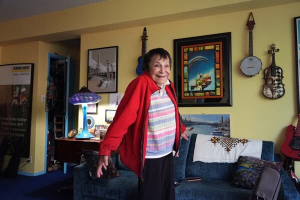 D’yan Forest smiles in the living room of her apartment, where musical instruments hang on the walls.