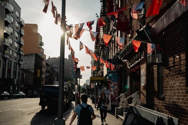 Small flags hanging on lines between a pole and a brick building.