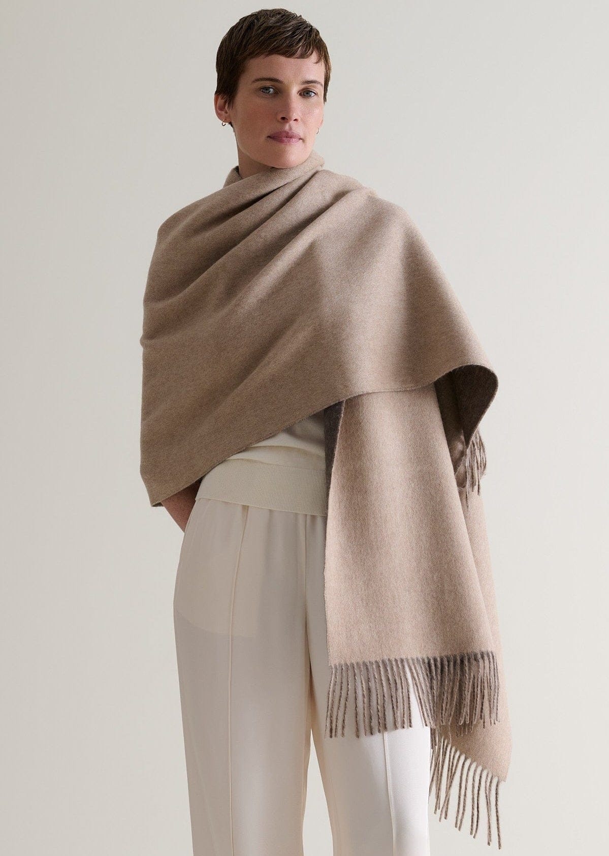 Image 7 of 7 showing woman wearing Rise & Fall's finest cashmere double faced wrap twine side with cream jumper and trousers.