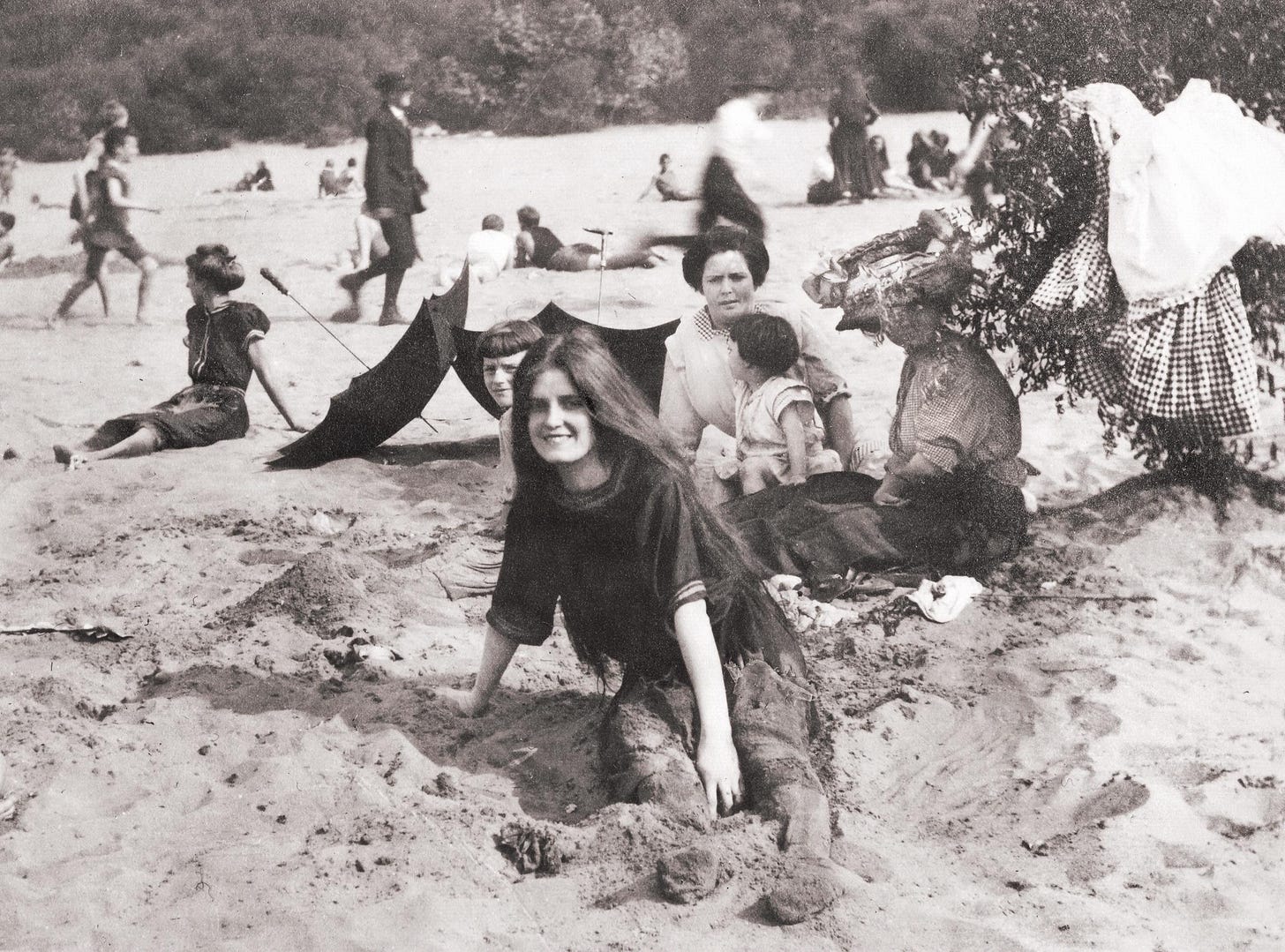 A lively beach scene featuring people enjoying the waterfront in Cincinnati, Ohio, circa 1910.