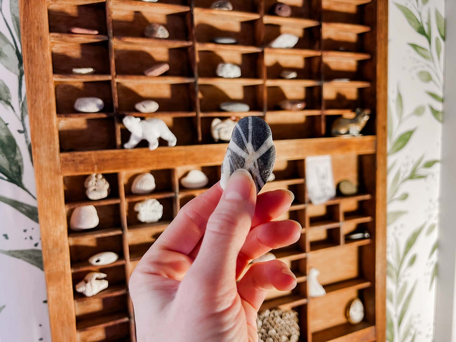 Photograph of graphic novelist K. Woodman-Maynard carrying a rock in her studio. The rock symbolizes completing milestones in her creative projects. 