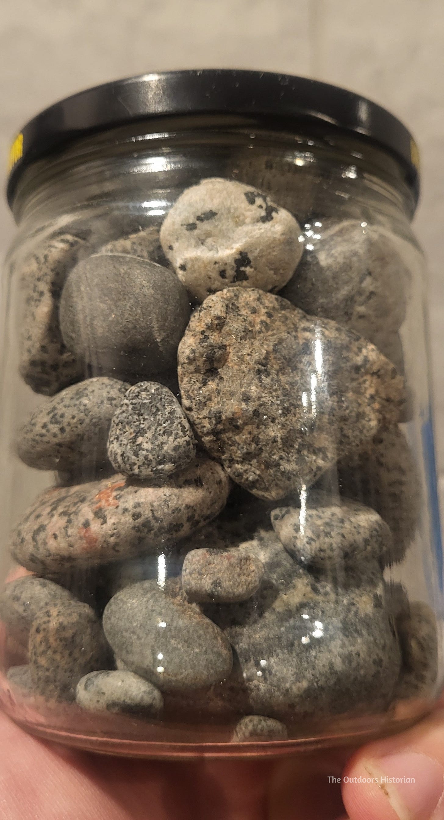 A jar of plain looking grey rocks.