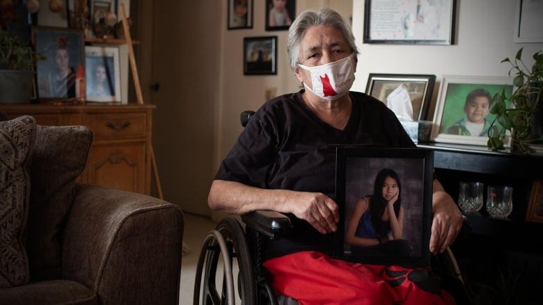 An elderly woman holds a portrait