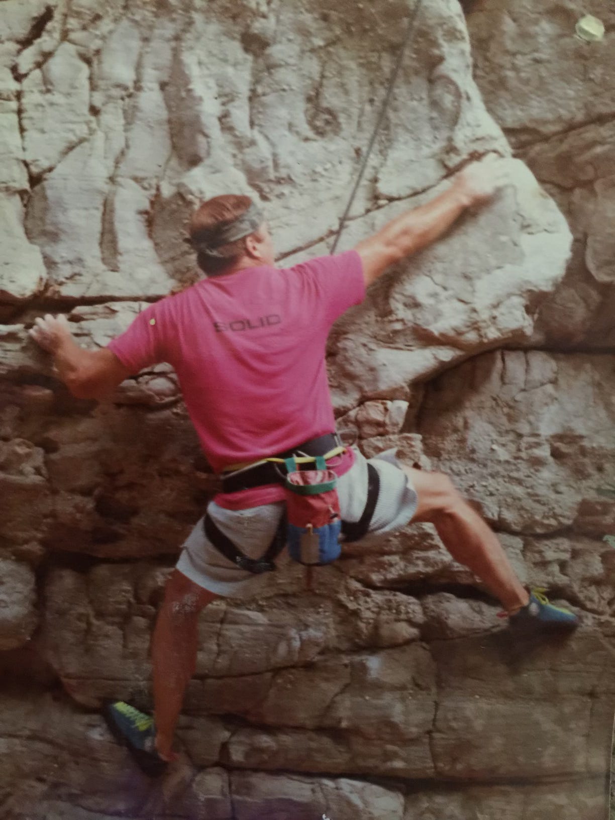 a man in a pink shirt rock climbing