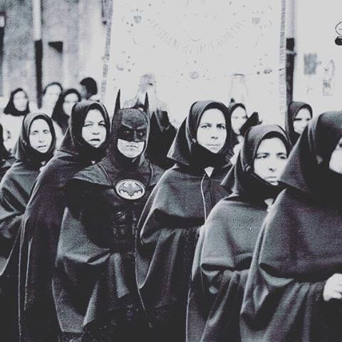 black and white photo of batman standing in a line of nuns