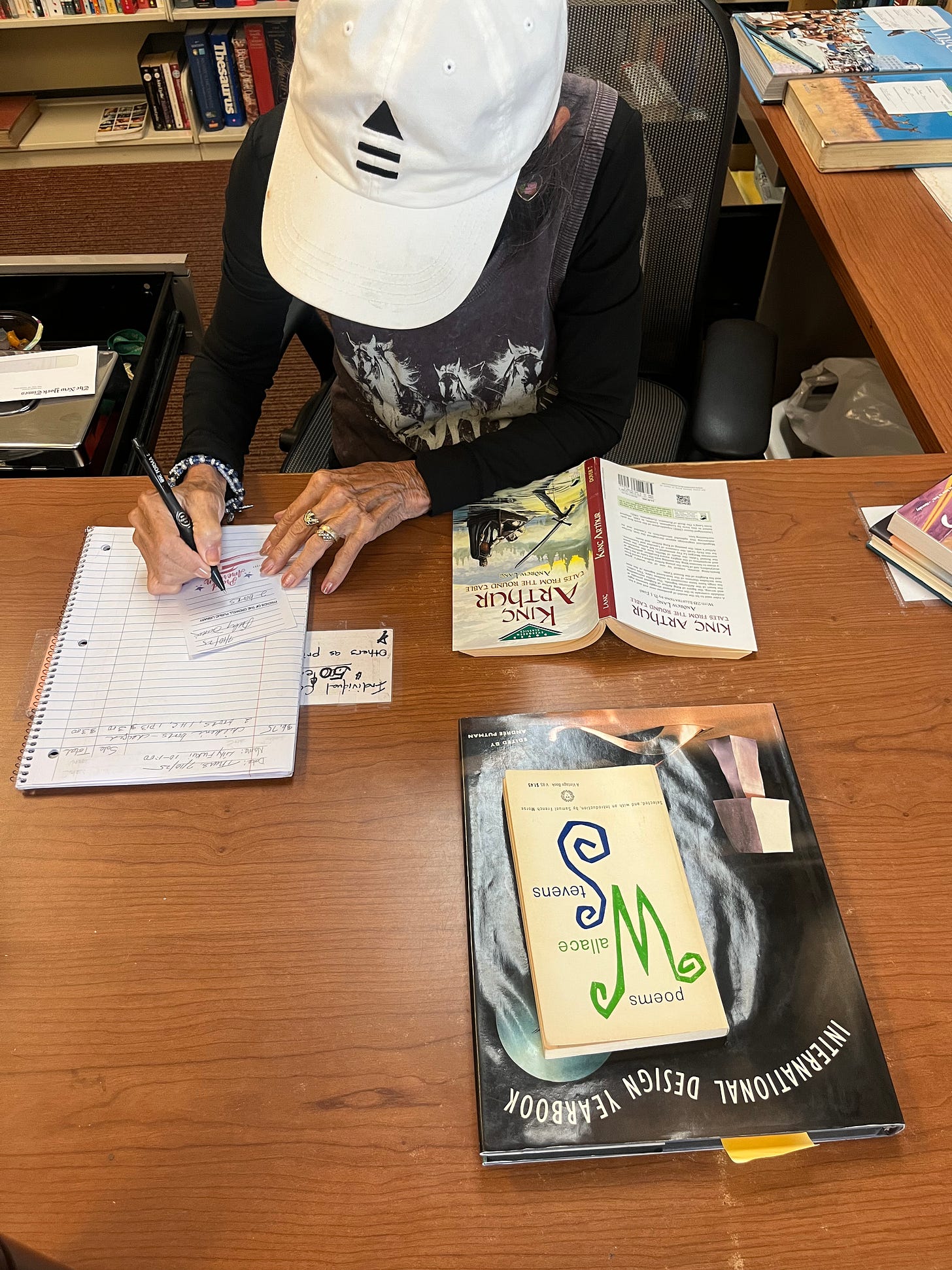 Woman hand writing a receipt on a table covered in books