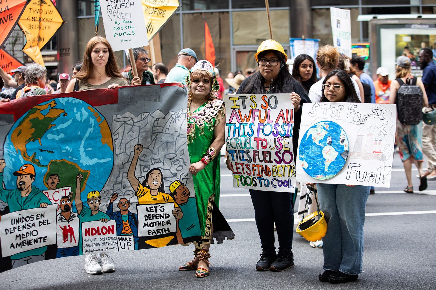A group of people stand carrying art and signs calling for an end to fossil fuels. A group of people stand carrying art and signs calling for an end to fossil fuels.