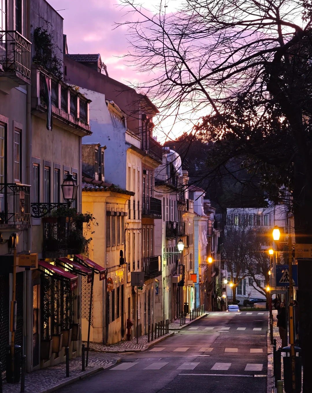 Lisbon at winter dusk. A residential street, not a postcard. This is what you're actually paying to live on