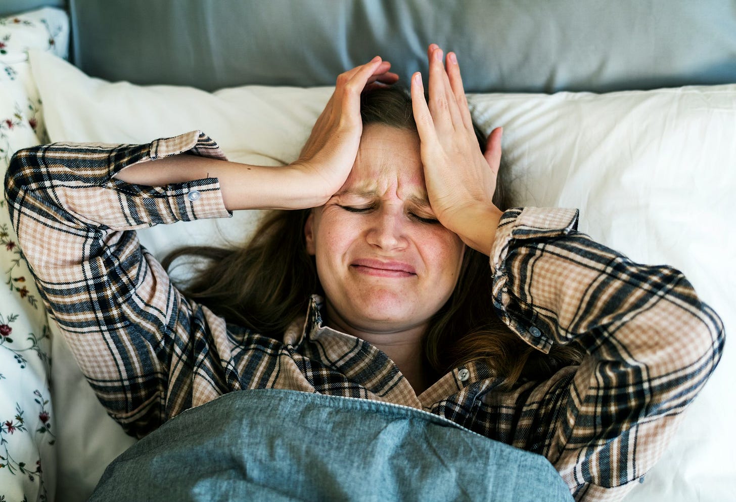 a woman holding her head in bed