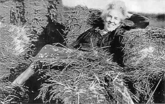 older woman laying in a pile of hay