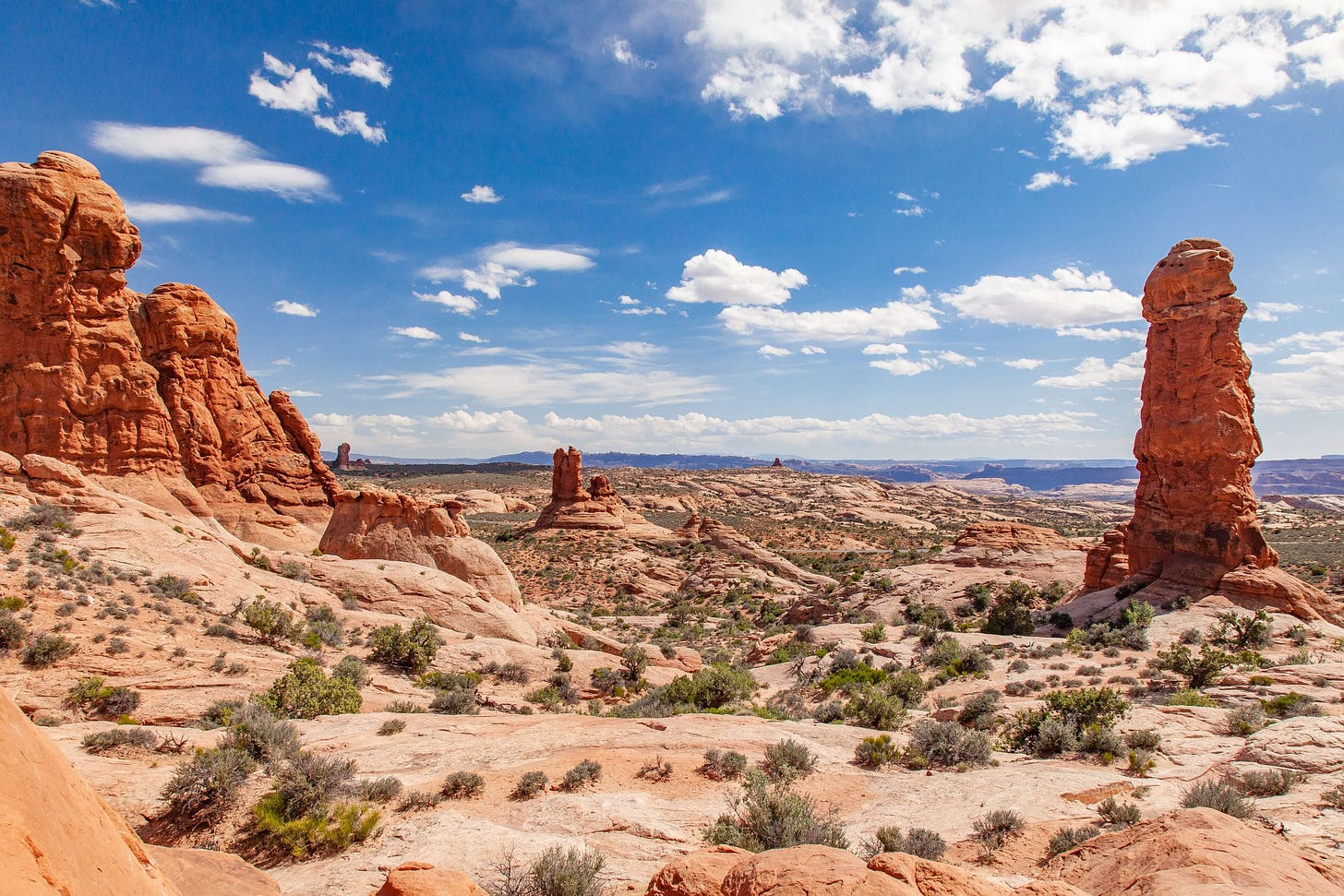 photo of orange desert with rocky protrusions and scrubby cacti