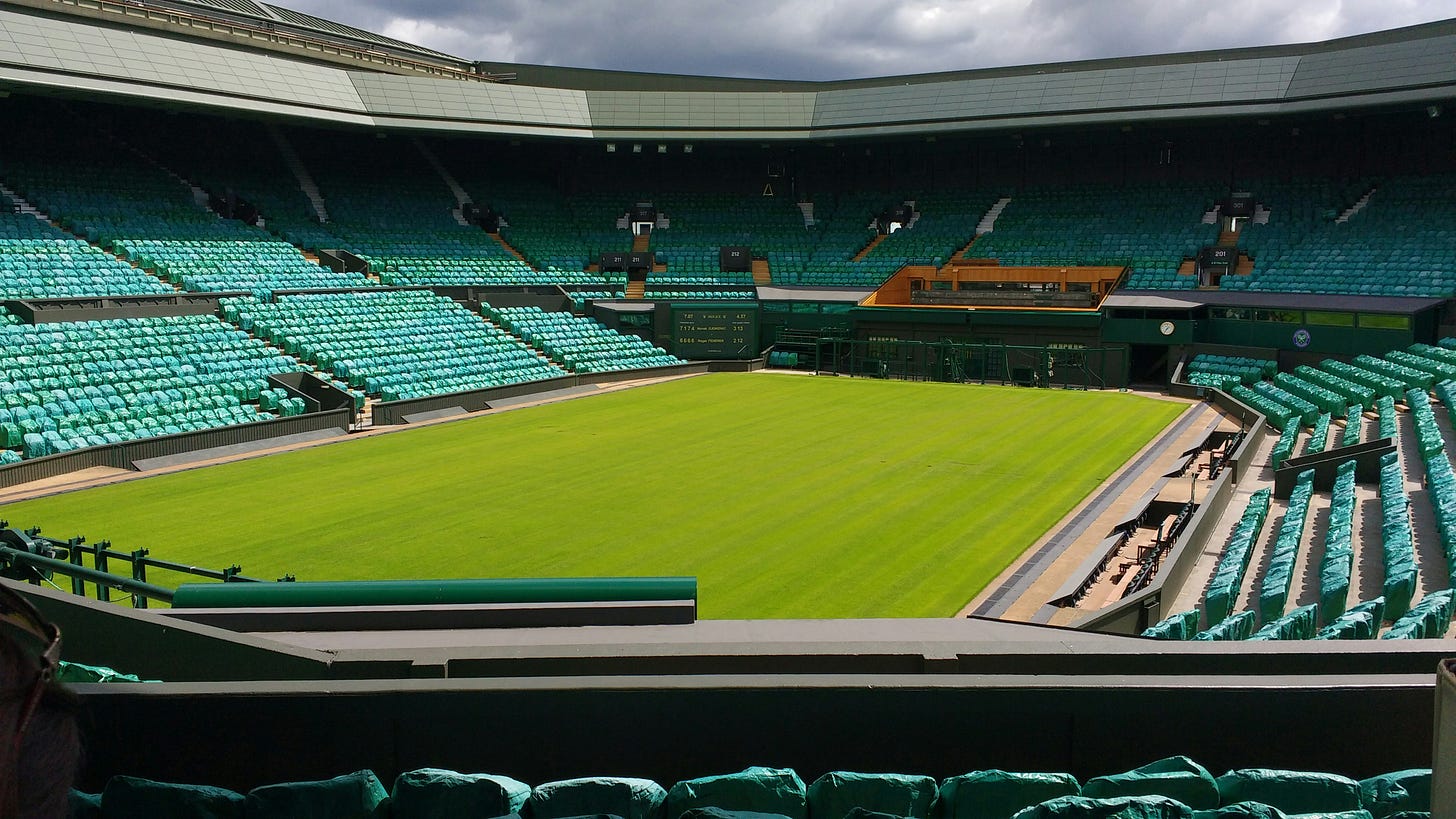 View of Wimbledon’s Centre Court with pristine green grass and surrounding empty stands.