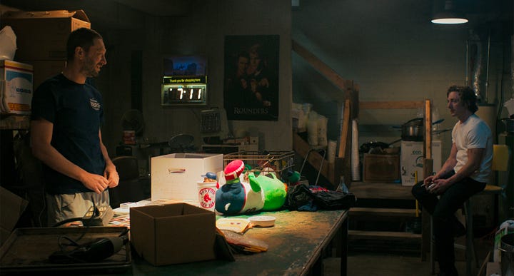 Richie and Carm talk in Richie's basement while in the background a neon sign ticks off time and temperature