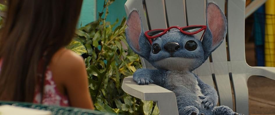 A blue fluffy alien (Stitch) lounging in a beach chair with sunglasses looking at a little girl (Lilo) who is slightly out of frame and out of focus. A blue fluffy alien (Stitch) lounging in a beach chair with sunglasses looking at a little girl (Lilo) who is slightly out of frame and out of focus.
