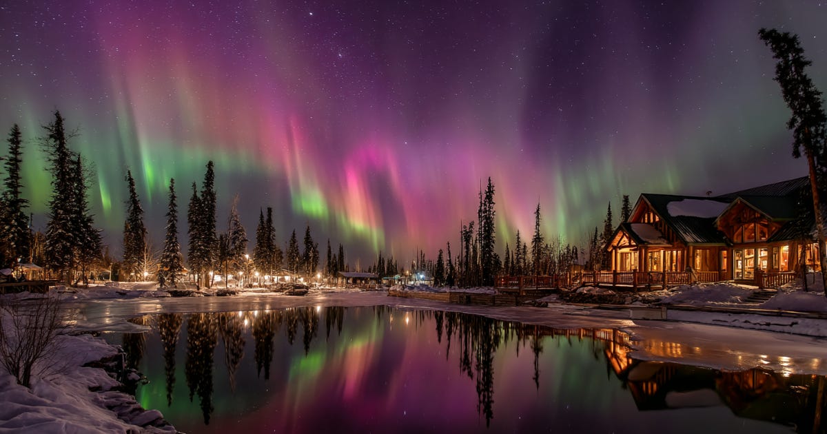 Northern Lights Canada over a frozen lake with a cozy snow-covered lodge. Northern Lights Canada over a frozen lake with a cozy snow-covered lodge.