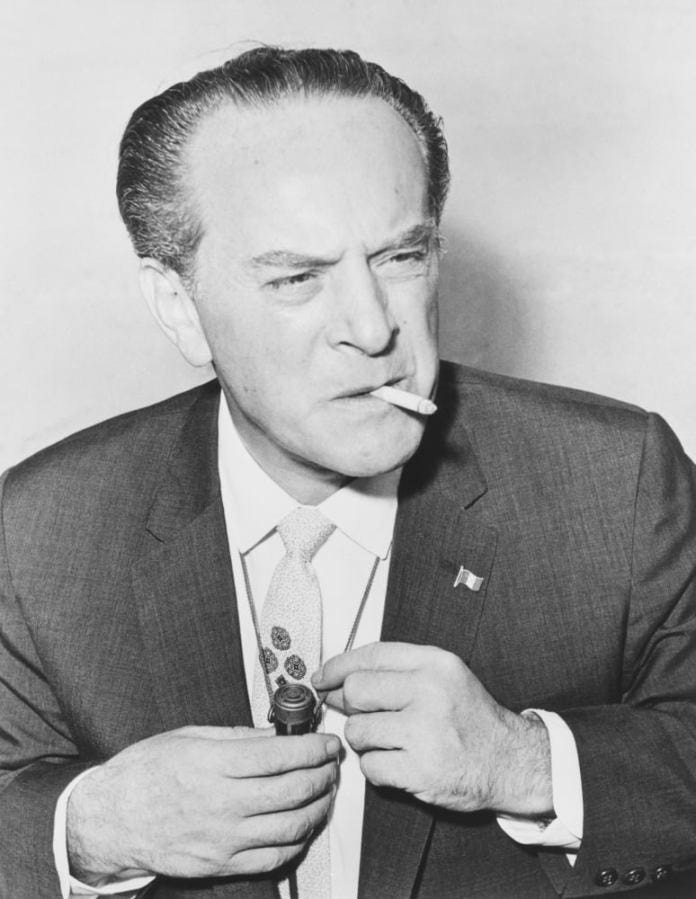 A person in a suit smoking a cigarette
Description automatically generated A person in a suit smoking a cigarette
Description automatically generated
