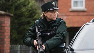 A woman carrying a large gun stands behind some card.