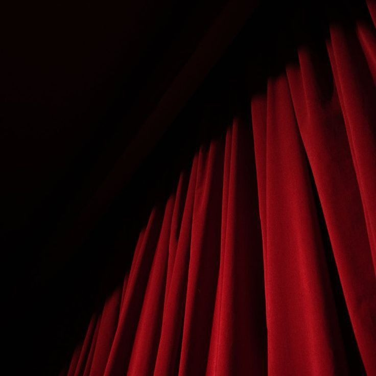 This may contain: a red curtain is open in the dark This may contain: a red curtain is open in the dark