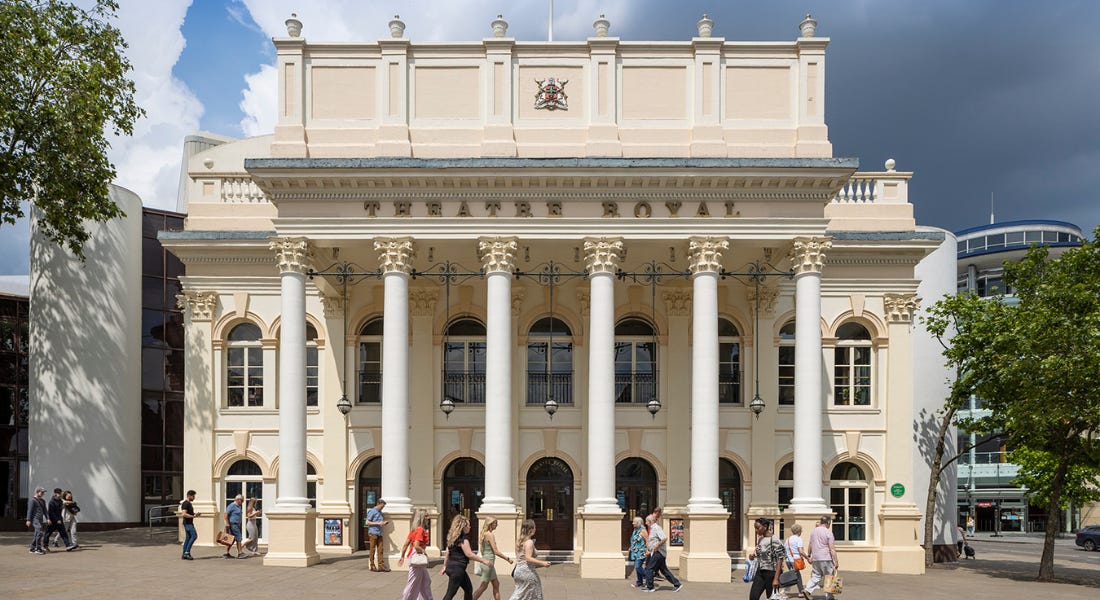 The Theatre Royal in Notitngham - a cream and white ornate building - with people walking in front of it