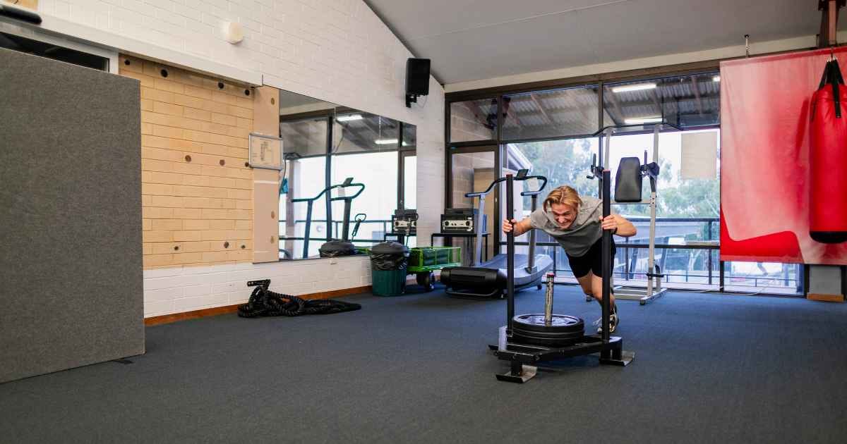 man pushing a prowler in a gym