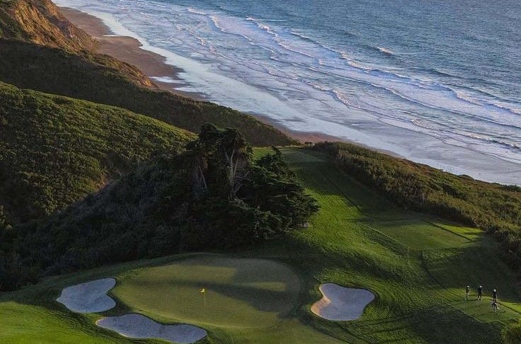 This may contain: an aerial view of a golf course overlooking the ocean and beach with people on it This may contain: an aerial view of a golf course overlooking the ocean and beach with people on it