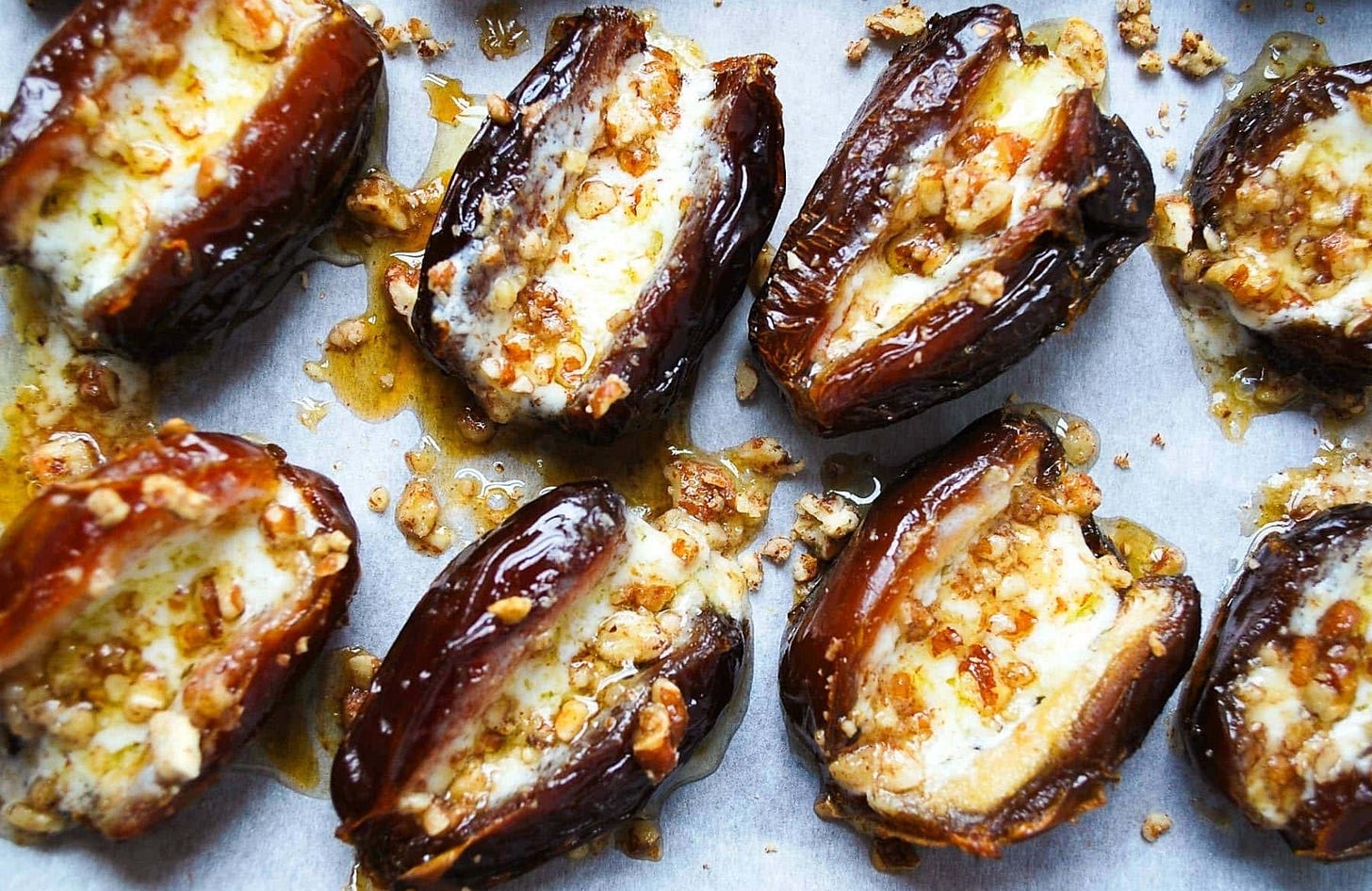 mascarpone stuffed dates with pecans and maple syrup baked on a cookie sheet with parchment paper
