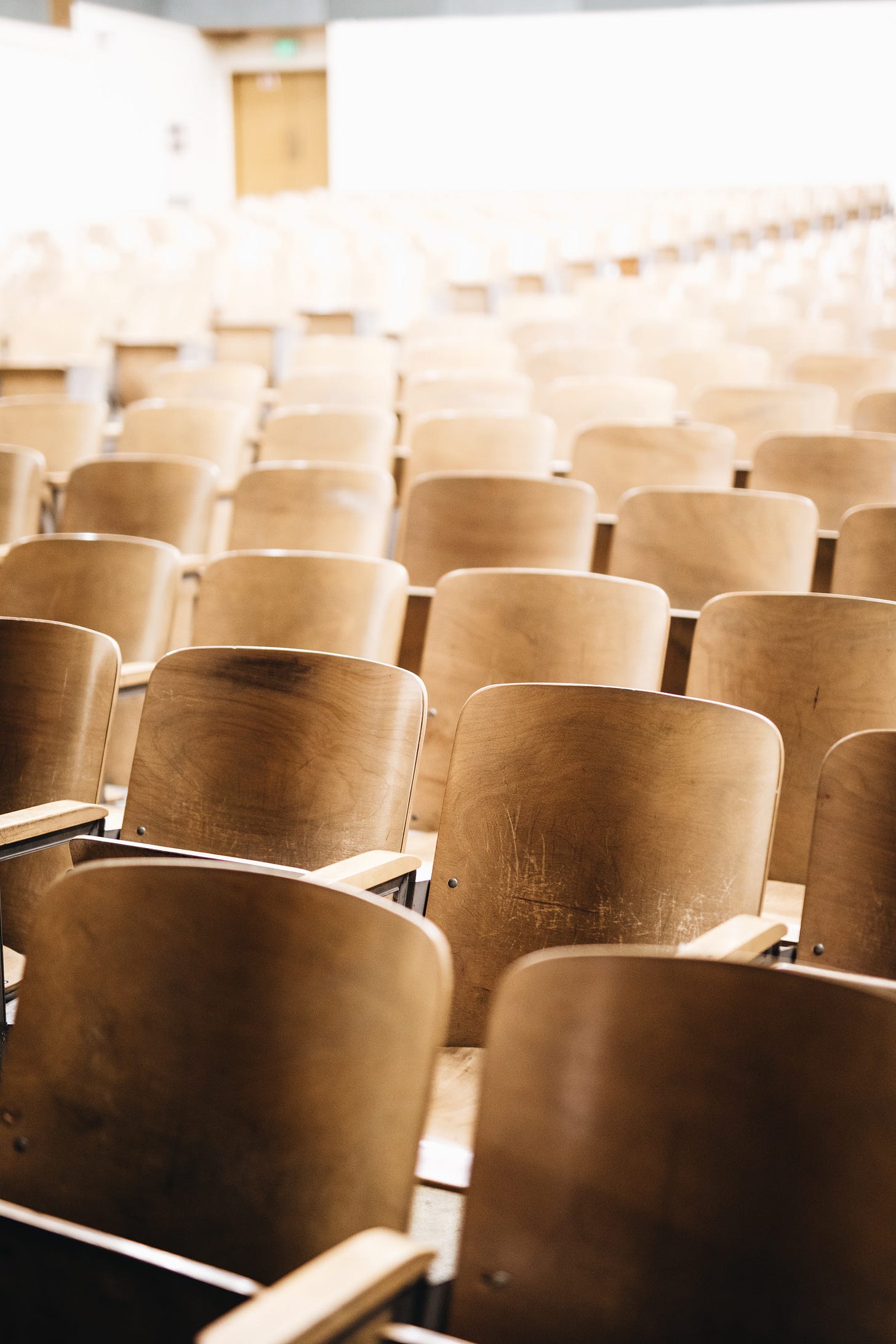 close-up of empty wooden chairs in an auditorium
