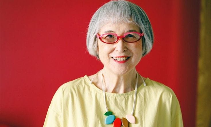 This may contain: an older woman wearing glasses and a necklace with colorful beads on it's neck