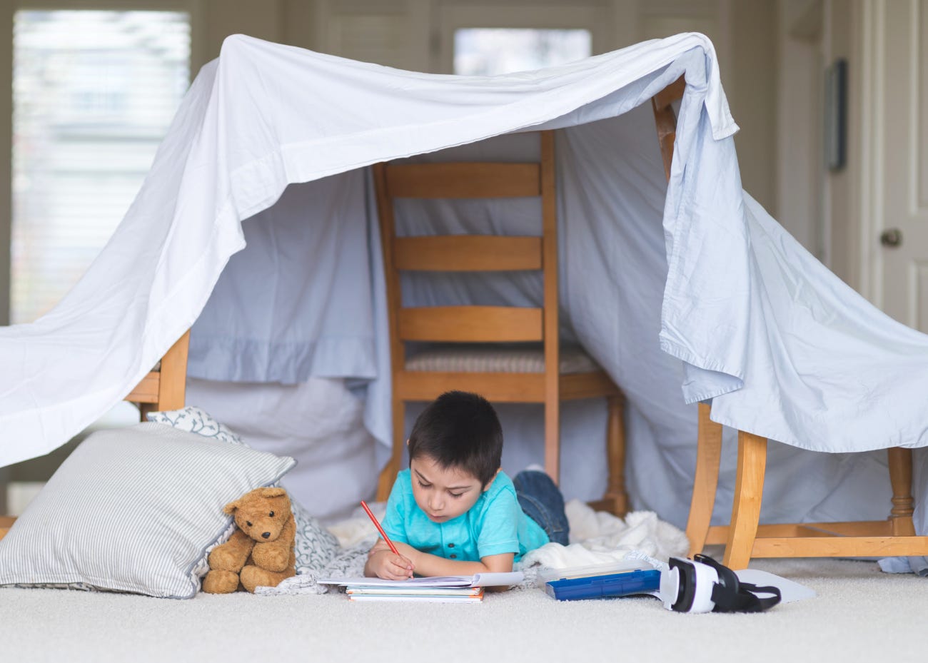 child writing under a play fort